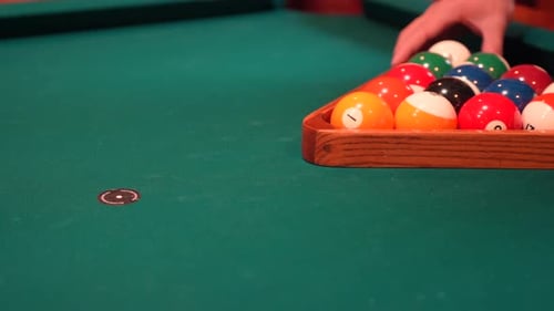 Person Racks 8 Ball Pool Triangle Closeup on the Spot with Solid and Stripped Billiard Balls on Tabl