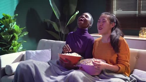 Friends Watching TV and Eating Popcorn Indoors