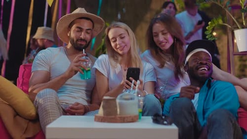 Friends Enjoying a Night Party Looking at Phone