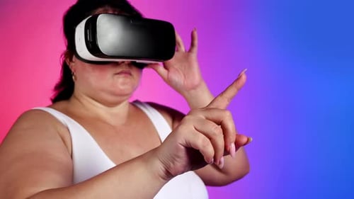 Woman with overweight in a tracksuit using VR headset in a studio with blue and red background