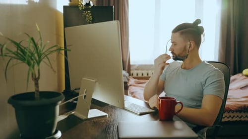 Side View of a Young Male Working at Home Using a Desktop Computer