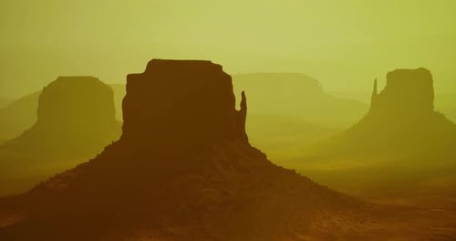 Monument Valley Landscape During Sunset in Warm Hues with Silhouettes