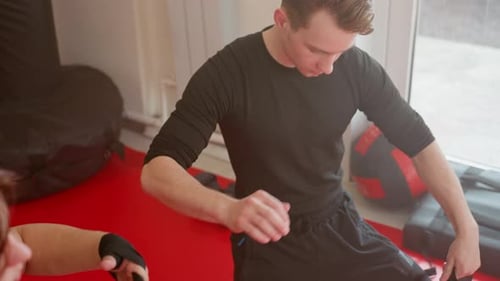 Athletes in Black Sportswear Unwrapping Hands on Red Mat in Gym