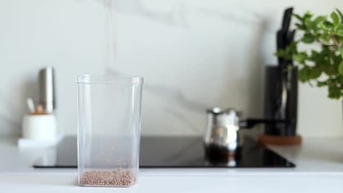 Filling Buckwheat Container on Bright Kitchen Counter