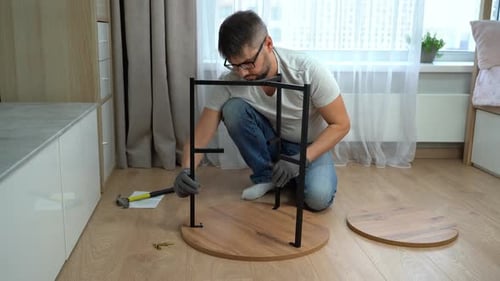 Man Assembling Round Table with Metal Legs Indoors