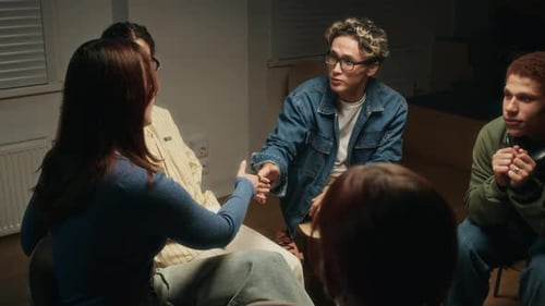 Group of young adults talking and shaking hands indoors