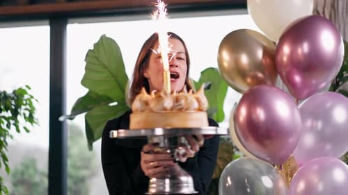 Woman Holding Birthday Cake with Balloons Indoors