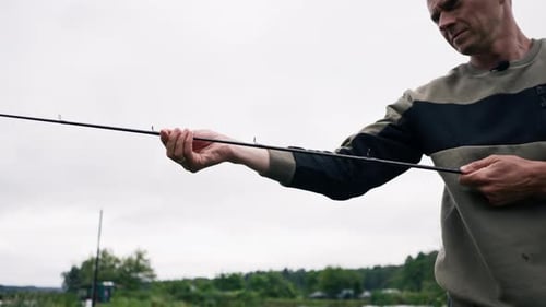 portrait Fisherman with fishing rod or spinning and professional tools sitting on the river fishing