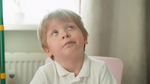 Boy With Blond Hair Writes at Table