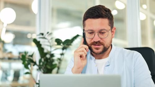 Man Talking on Phone While Using Laptop