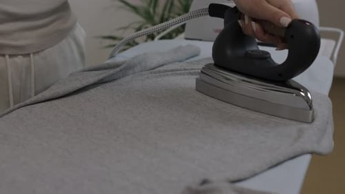 Close up of female hands ironing clothes with iron on an ironing board. slow motion, 4k footage