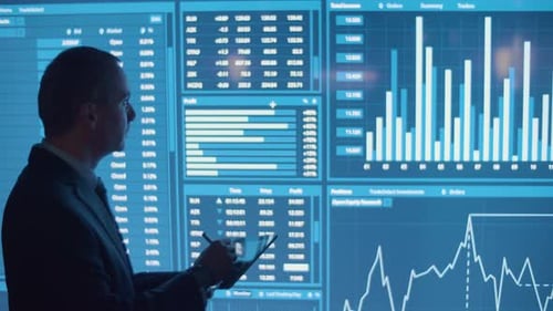 Homme écrivant des données sur une tablette à partir d'un grand écran numérique