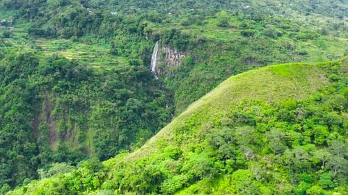 Mountains Covered with Jungle and a Waterfall in the Distance Aerial View