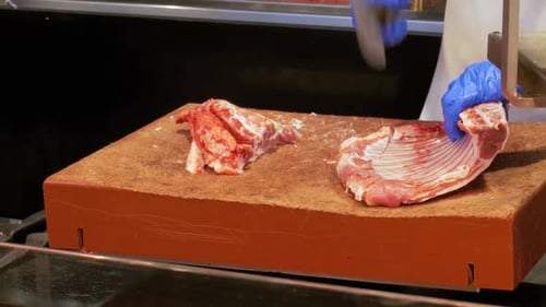 Butcher Cutting Raw Meat of Beef Ribs With Knife in the Market of La Boqueria Barcelona Spain