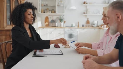Senior Man and Woman Signing Mortgage Contract Meeting with Real Estate Broker African American