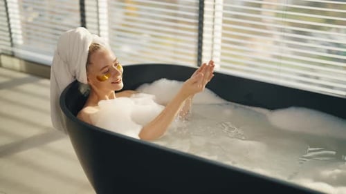 Woman Relaxing in Bathtub with Cosmetic Patches