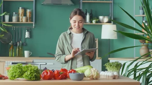 Woman Uses Tablet for Recipes in Kitchen