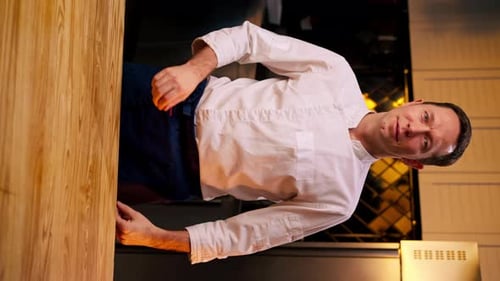 Chef Smiles in Kitchen Wearing Chef's Coat and Apron