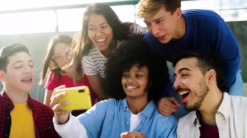 Diverse group of friends using mobile phone and laughing in park