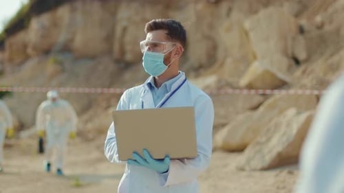Scientist Using Laptop Outdoors Near Boulders
