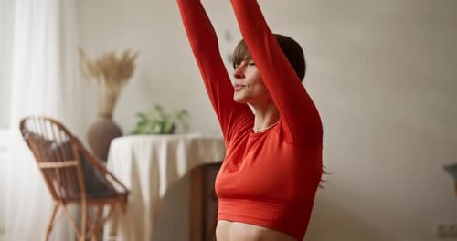 Woman Stretches at Home in Orange Workout Outfit