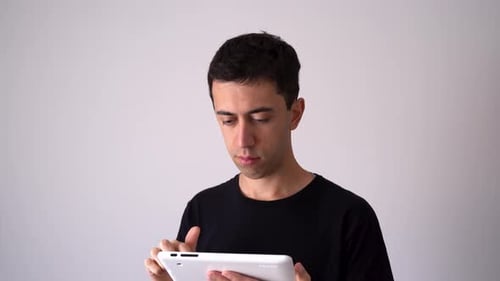 Focused Young Adult Uses Tablet Device Indoors