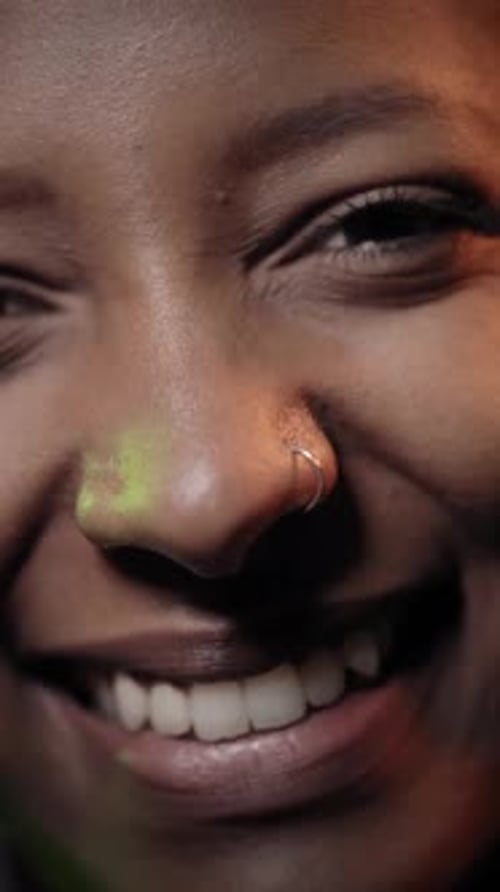 Portrait d'une fille heureuse et confiante regardant la caméra souriante dans un éclairage au néon coloré multicolore
