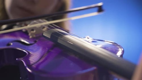 Close-up of young female musician playing violin on stage and her violin.