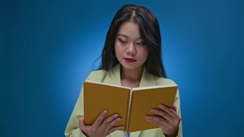 Smiling Woman Holding Notebook on Blue Background