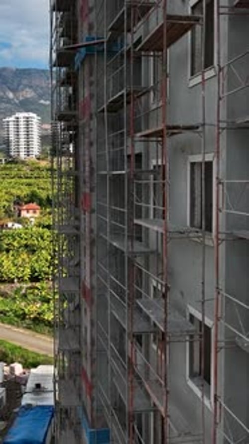 Vídeo vertical: fachadas de edificios, trabajadores de la construcción en andamios, rica infraestructura cautivadora