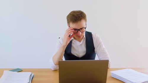 Jeune professionnel concentré sur le travail au bureau avec un ordinateur portable et des papiers