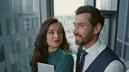 Couple Business Partners Talking Joyfully Standing Near Panoramic Window Close Up. Cheerful Colle...