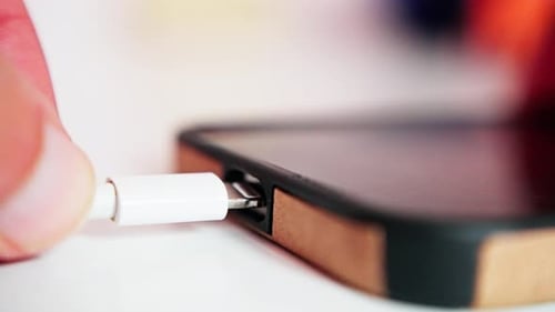 Closeup Phone Charging Cable Being Plugged Into Smartphone Port By Fingertip Warm Shallow Depth of