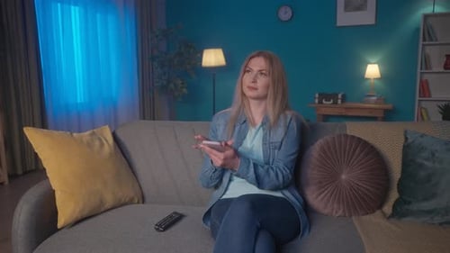 Blonde Woman Relaxes on Couch Watching TV at Night