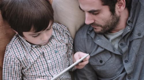 Father and Son Using Tablet at Home Together