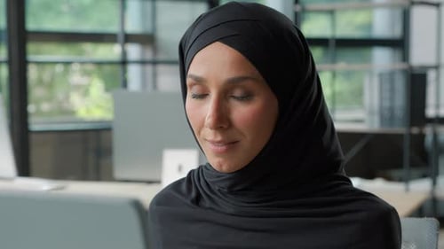 Glückliche positive muslimische Geschäftsfrau im Hijab, die im Büro lächelt Arabisch-ethnische islamische Geschäftsfrau