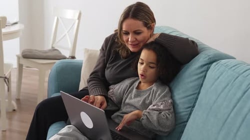 Woman and Child Use Laptop on Sofa