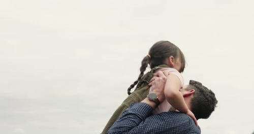 Dad Lifts Daughter, Hugs, and Smiles Outdoors
