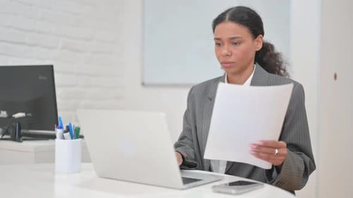 Woman Works at Laptop, Reads Documents, Reacts Positively