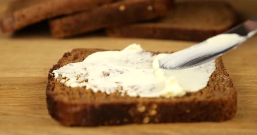 Butter Being Spread on a Slice of Dark Bread