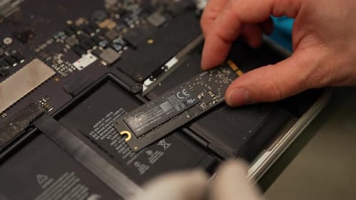 Professioneller Computermaster, der das Solid-State-Laufwerk (Ssd) während des Computers über dem geöffneten Laptop hält