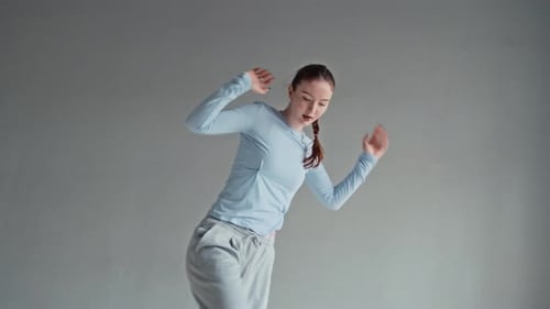 Female Zoomer Freely Dancing to Music in Minimalist Studio