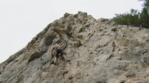 Alpinist Climbing Up Rock with Rope