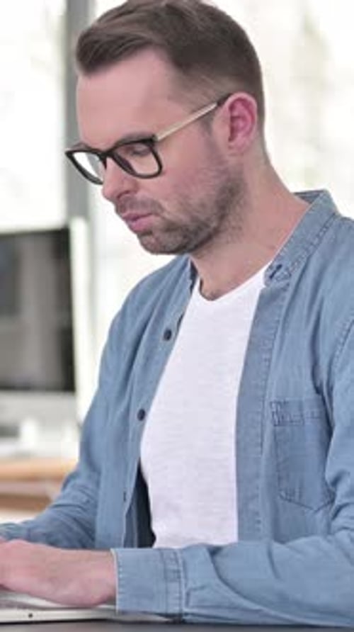 Man Wearing Glasses Working on Computer Indoors
