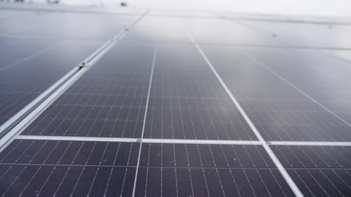 Nahaufnahme von Sonnenkollektoren, die den bewölkten Himmel reflektieren und grüne Energie erzeugen
