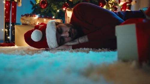 Man Sleeping by Christmas Tree with Gifts