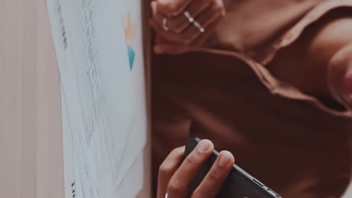 Close Up of Woman Hands with Mobile Phone and Business Documents Lying on Table
