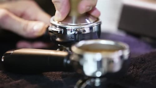 Barista Tamping Coffee Grounds in Portafilter Close Up