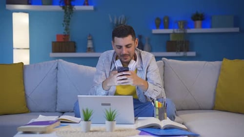 Young Man Smiling and Texting on Phone at Home