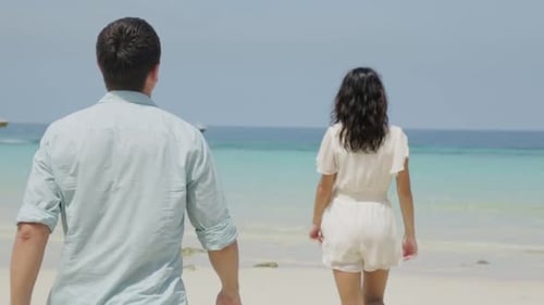 A Couple Leisurely Walks on the Beach Enjoying the Beautiful Ocean View Nearby